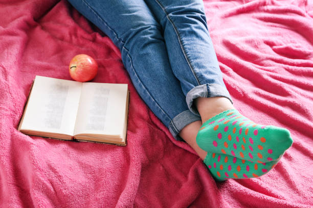 istock Woman with book and apple sitting on pink plaid 2197644749