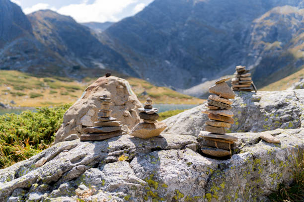 Stone cairns arranged on rocky terrain with majestic mountains in the background, symbolizing balance and tranquility in a natural alpine setting