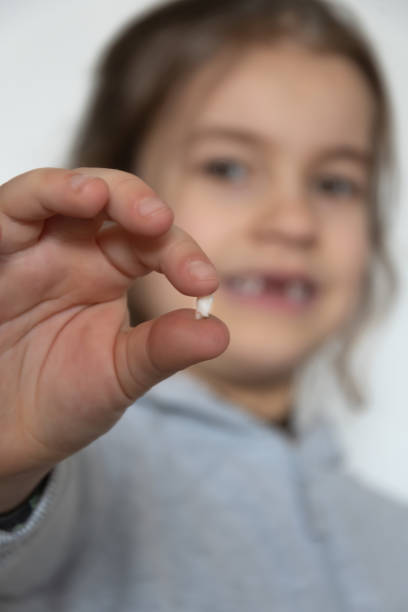 istock A little girl happily shows off her first lost tooth on camera. 2197647394