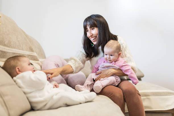 istock Happy mother bonding with adorable twin babies on sofa. 2197648520