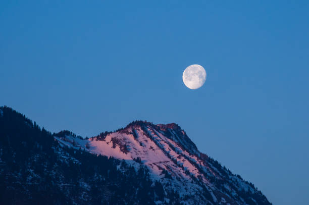 istock Snowy Mountain Peak at Dawn with a Large Full Moon 2197649157