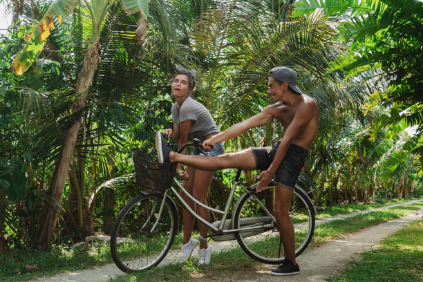 istock Young couple enjoying a fun moment with a bicycle on a scenic tropical pathway 2197650644