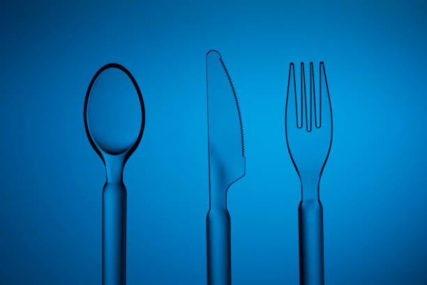 Transparent plastic cutlery -spoon, knife and fork,-  shot on deep blue background with a levitation effect