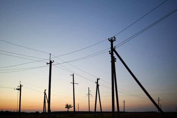 High voltage line power post with electricity pylons in evening sunset yellow blue light