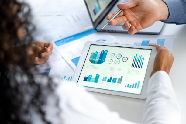 istock Close up of three people looking at financial data with graphs and charts. 2197655194
