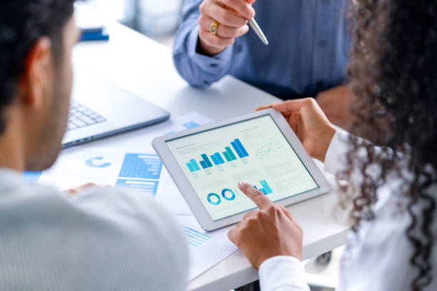 primer plano de tres personas mirando datos financieros con gráficos y tablas. - portafolio fotografías e imágenes de stock