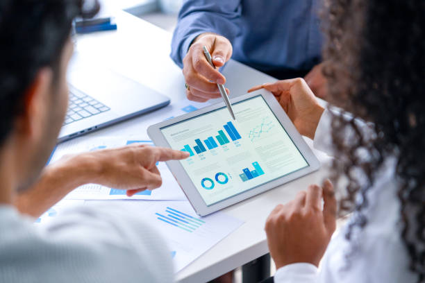 istock Close up of three people looking at financial data with graphs and charts. 2197655349