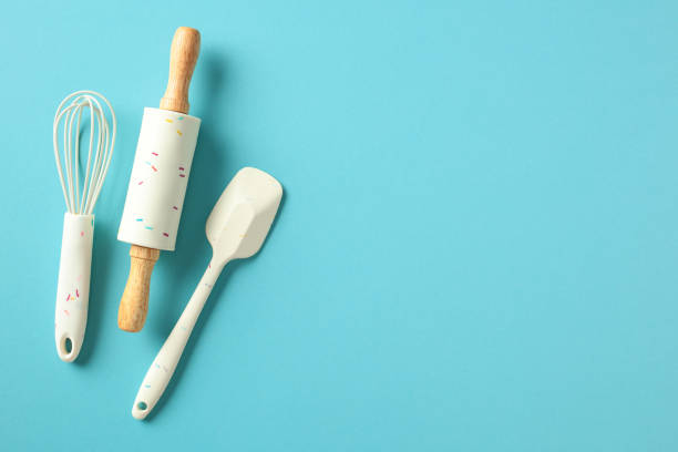 istock Kitchen utensils on a blue background: a whisk, rolling pin, and spatula with wooden handles and white silicone parts decorated with colorful sprinkles. Perfect for baking and cooking themes 2197657761