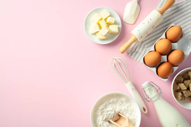 istock Baking ingredients and tools on a pink background: butter, eggs, flour, sugar, milk, whisk, rolling pin, and spatula. Flat lay, top view, copy space 2197658426