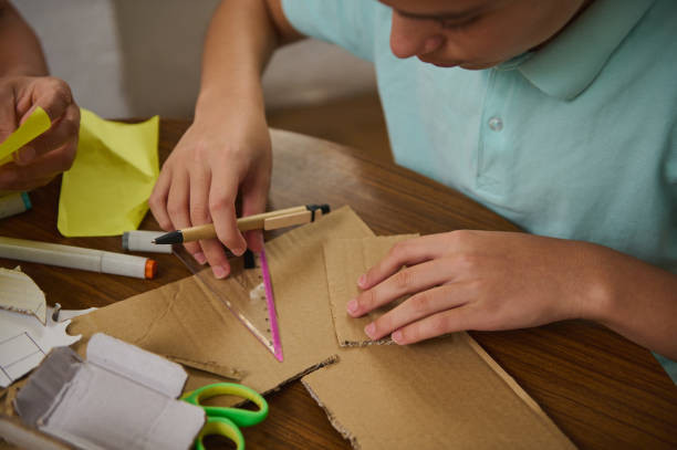Young student engaging in crafts with recycled cardboard and measuring tools