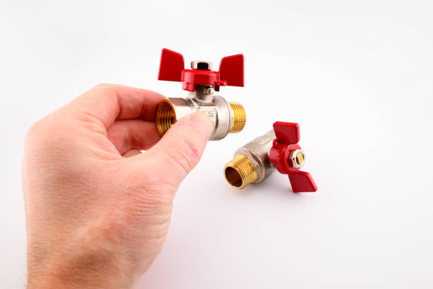 man holding bronze or brass threaded water ball valve with red handwheel or wing in hand, home plumbing concept