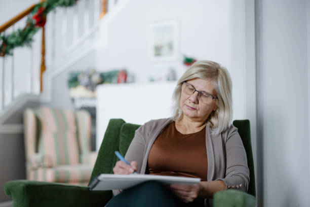 istock Senior Woman Writing in a Notebook in a Cozy Home Setting 2197674085