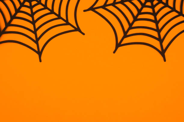 istock Black spider webs against a vibrant orange backdrop for Halloween decoration 2197674506