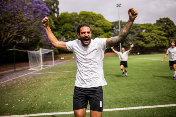 Soccer player shouts in excitement and celebrates a successful goal with a powerful expression of joy on the field.