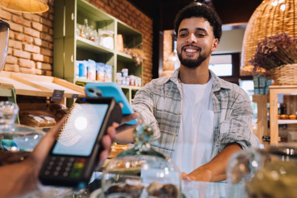istock Smiling customer paying for merchandise with his mobile phone 2197678703