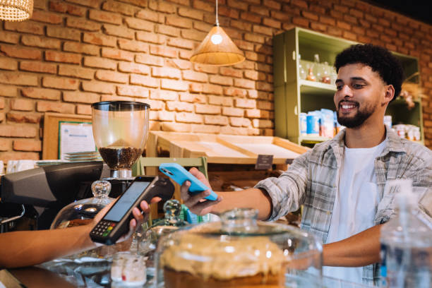 istock Smiling customer paying for merchandise with his mobile phone 2197678705