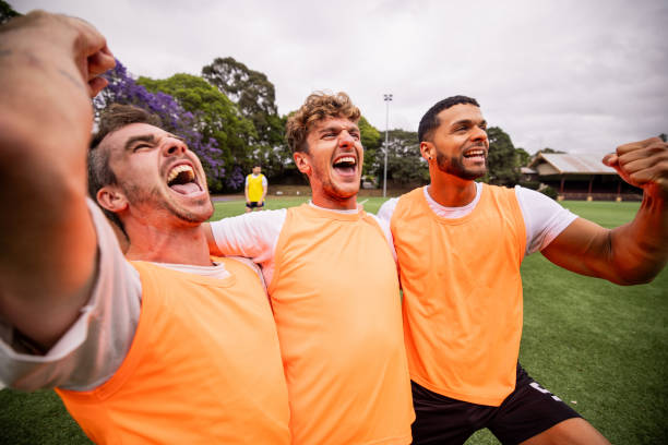 Boys sports team celebrating victory. Happy children winning the game. Kids football team huddling in a circle and jumping in happiness. Youth sports team succeed in tournament match