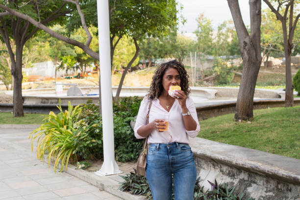 istock Latin woman enjoying a snack in a park 2197679994