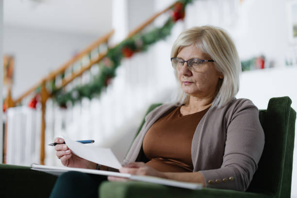 istock Mature Woman Focused on Paperwork Sitting in a Festive Home Setting 2197683782