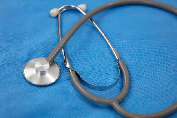 Medical stethoscope on blue doctor uniform background, closeup view