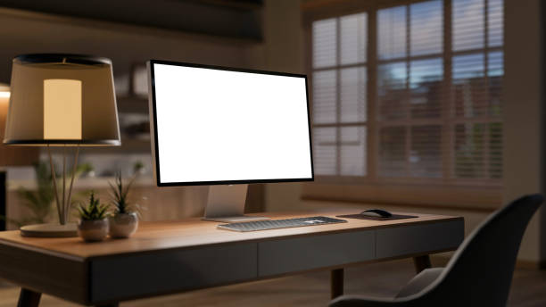 istock A computer placed on a hardwood desk in a cozy office at night with a warm light from the table lamp 2197694512