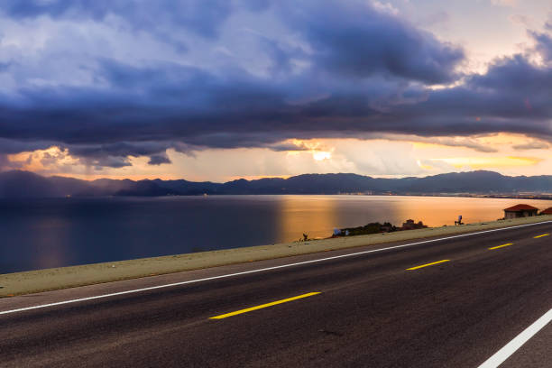 empty asphalt road near lake during sunrise. copy space for car.