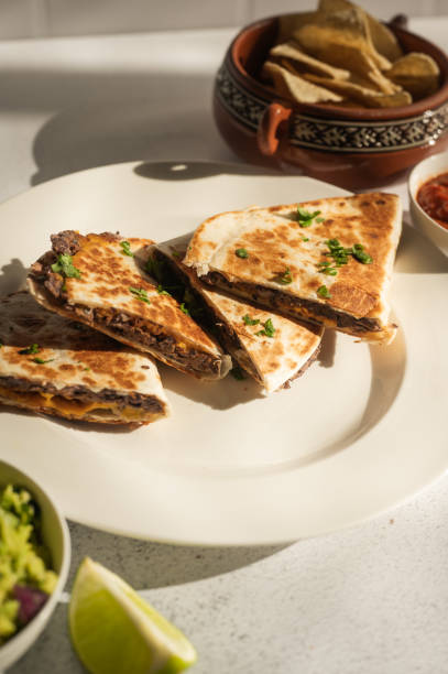 istock Vegan black bean quesadillas with guacamole, salsa, and chips on white 2197695184