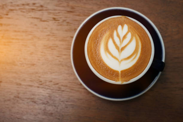 istock Latte art on a coffee cup on a wooden table in the warm sunlight. 2197697845