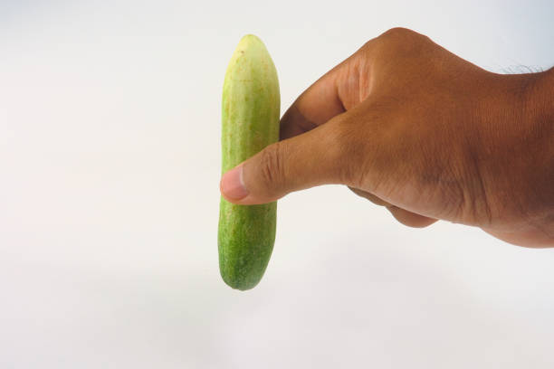 A hand holding a fresh green cucumber, isolated on a white background, symbolizing freshness and healthy lifestyle ideals