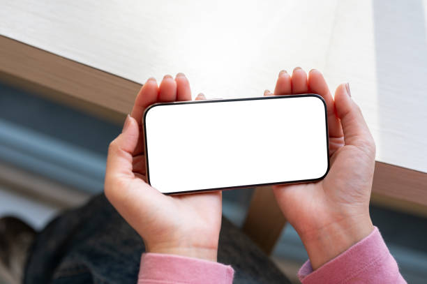 istock A close-up top view of a woman's hand holding a smartphone horizontally while watching a video. 2197710379