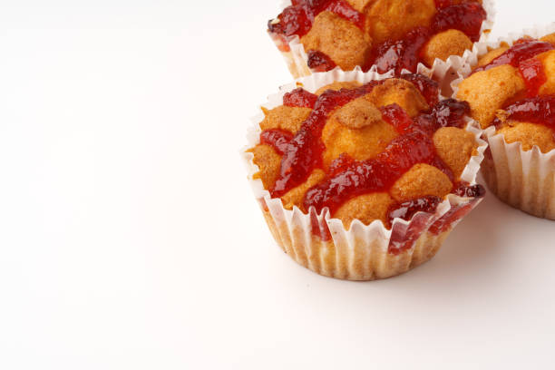 Freshly baked muffins are topped with vibrant red jam and scattered nuts, offering a tempting treat perfect for dessert or snacks. Ideal for any gathering or celebration.