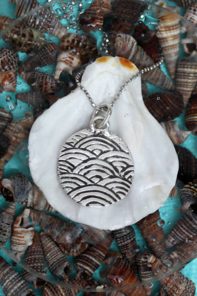 istock Elegant handmade silver round pendant with chain featuring a beautiful wave pattern on sea shells. 2197710611