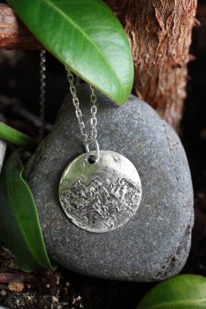 istock Silver chain with handmade pendant with a mountain range design on stone with tree and leaves. 2197710618