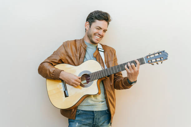 istock Musician playing acoustic guitar and smiling on white background 2197711711