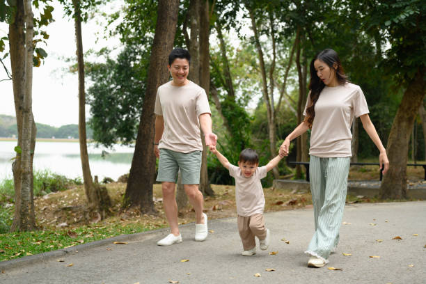istock Happy family walking together along a park path, holding hands 2197712833