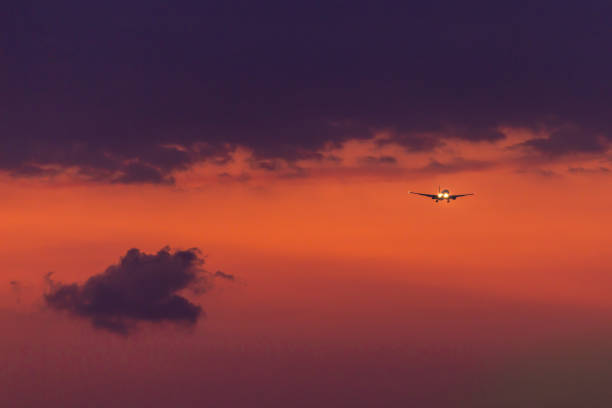 An Airplane with its landing gear down is approaching at Phuket International Airport for landing at sunset.