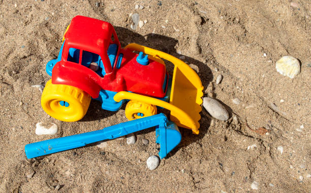 3D rendered sand castle and plastic beach toys on real sand photo backgorund. Large copy space with bright sunlight feeling.