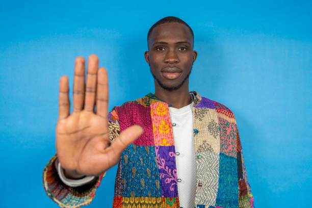 istock Young man showing stop sign with hand on blue background 2197722517