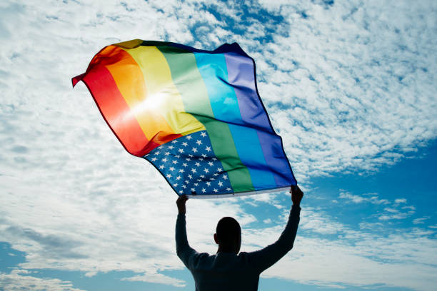 istock LGBTIQ person waving a rainbow US flag on the sky 2197724280