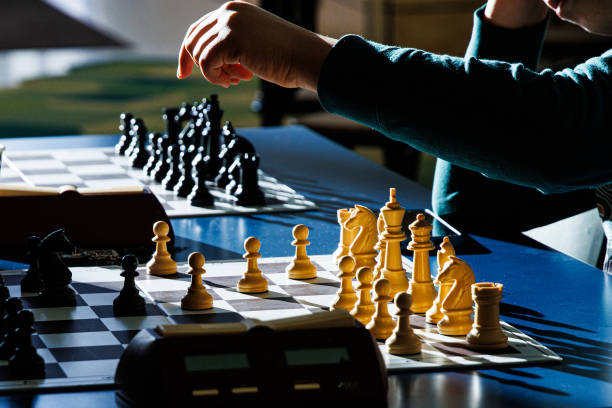 istock Closeup of chess players hands moving chess pieces on a board with a timer, making strategic moves on a tournament board, symbolizing focus, intelligence, and tactical decision making. Selective focus 2197725501