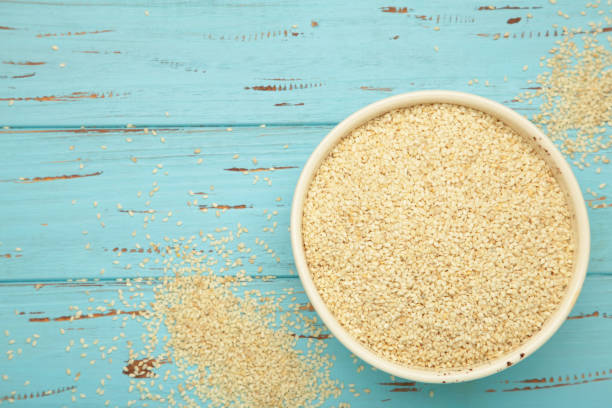 istock Raw sesame seeds in bowl on blue wooden background. 2197725659