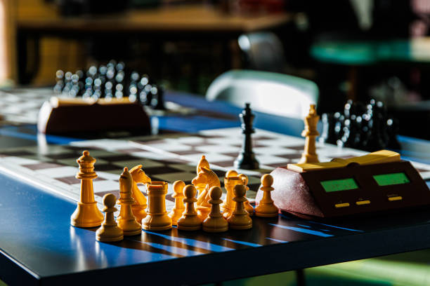 istock Chess pieces illuminated by sunlight on a tournament table with blurred background. Closeup of a chessboard with a digital timer, showcasing the contrast between light and dark. Selective focus 2197726074