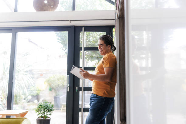 istock Man reading a book in a bright room at home 2197726297
