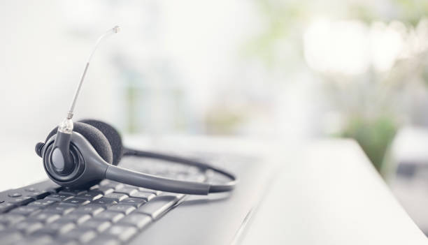 istock Headset headphones telephone with microphone on desk in support and customer service help desk call center background 2197730857