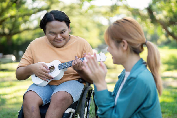 istock Young man in a wheelchair playing ukulele while a friend claps in admiration. 2197731543