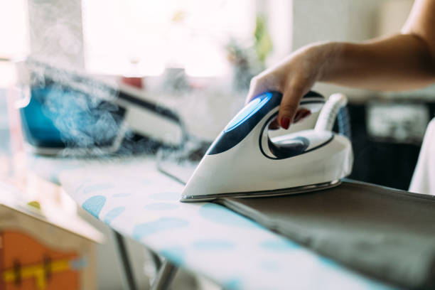 istock Person Ironing Clothes with a Modern Steam Iron in a Bright Room 2197734077