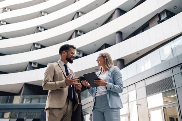 istock Business people having conversation holding digital tablet outside office building 2197738339