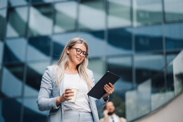 istock Businesswoman smiling and using digital tablet outdoors 2197738367