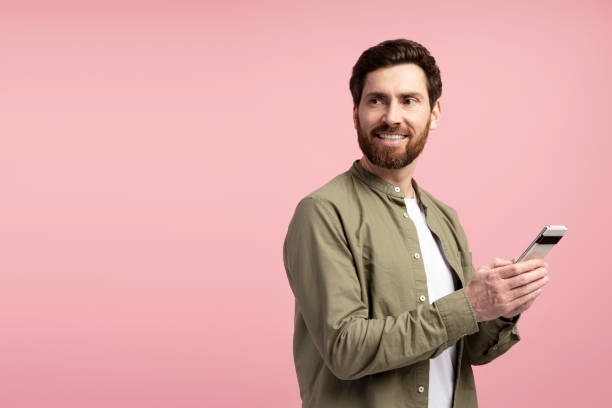 istock Handsome young man with smartphone looking away on copy space on pink background 2197740234