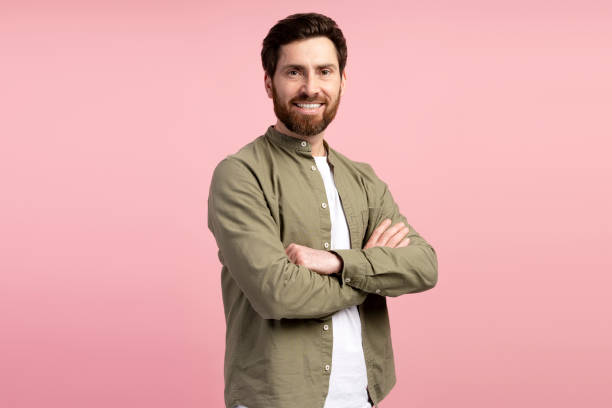 istock Happy man crossing arms standing isolated on pink background looking at camera 2197740256